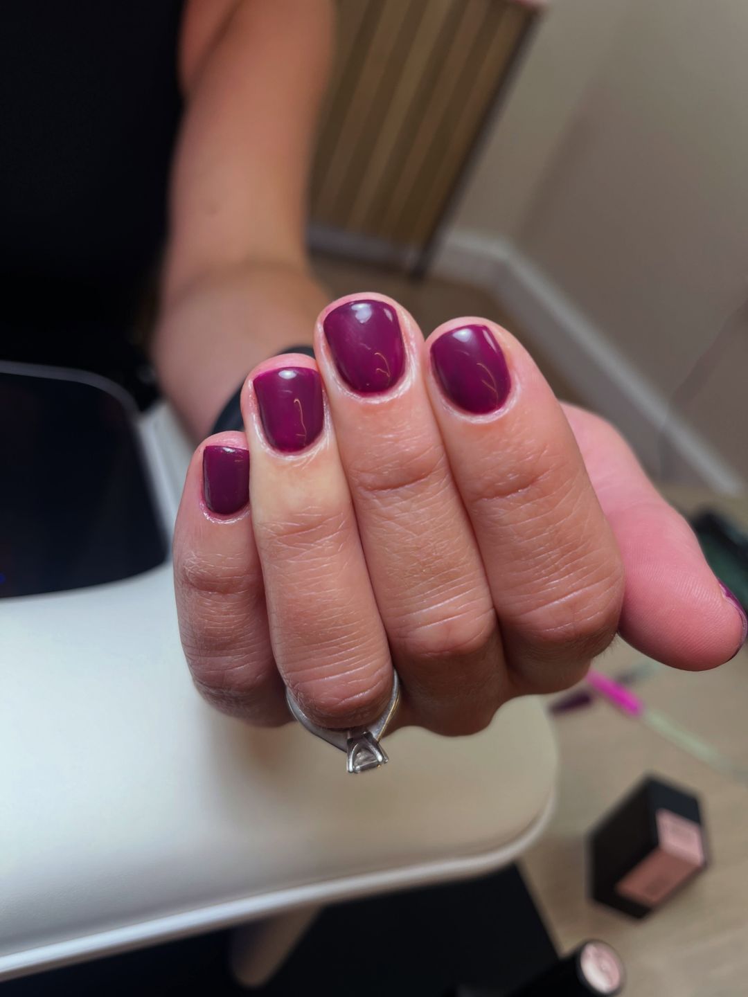 Short natural nails painted in a deep sugarplum gel